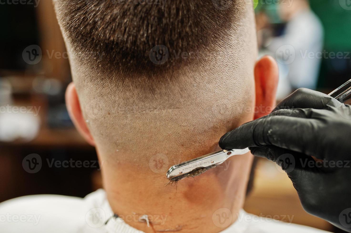 Handsome bearded man at the barbershop, barber at work. Close up nape. photo