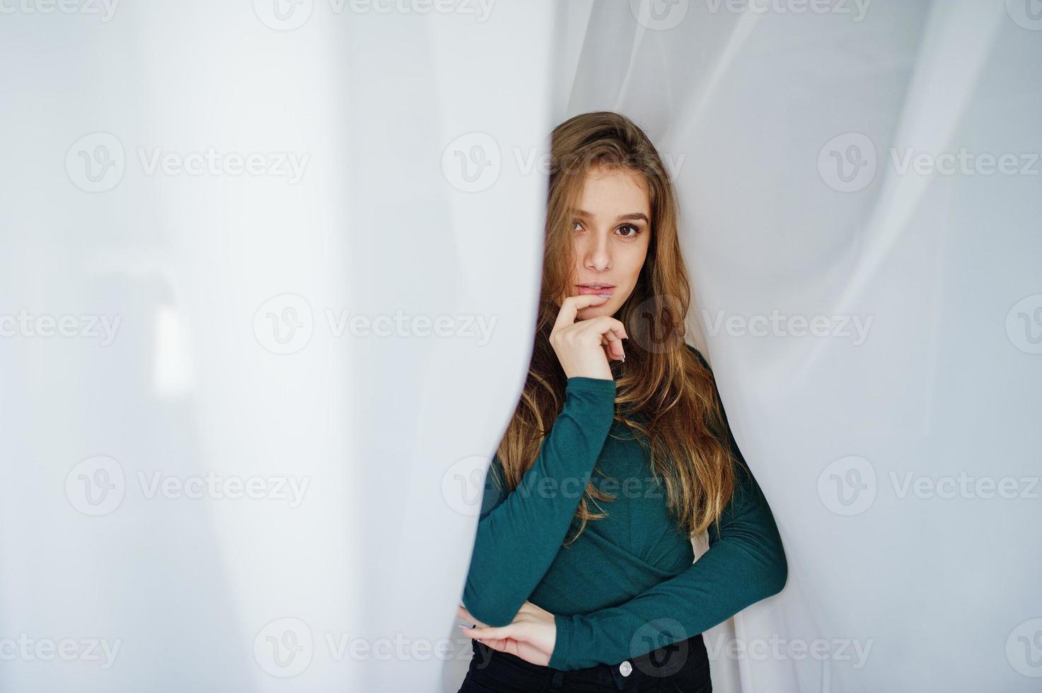 Handsome brunette girl wear on green, posing at curtains. Studio model portrait. photo