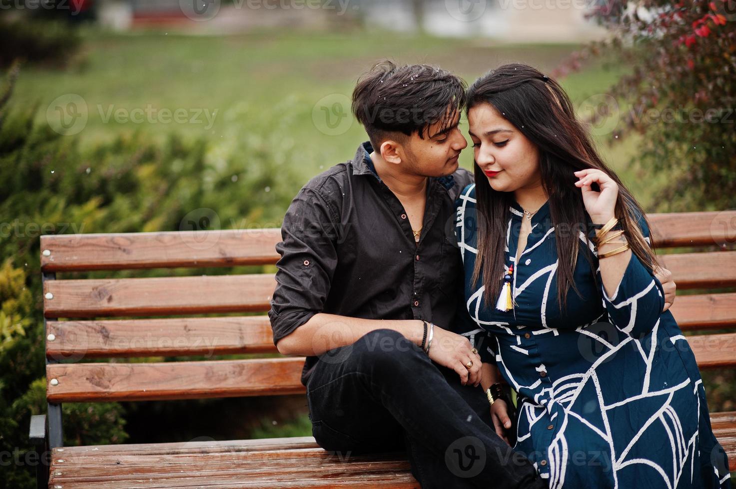 Love story of indian couple posed outdoor, sitting on bench together. photo