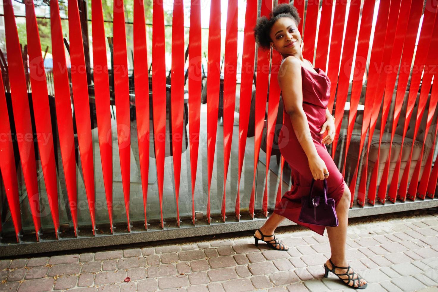 Portrait of a beautiful natural young African woman with afro hair. Black model in red silk dress. photo