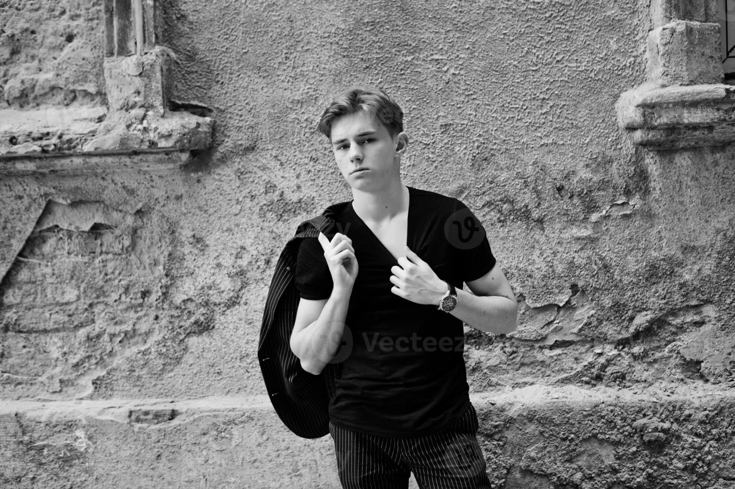 Young stylish macho boy in black jacket posed outdoor of street. Amazing model man. photo