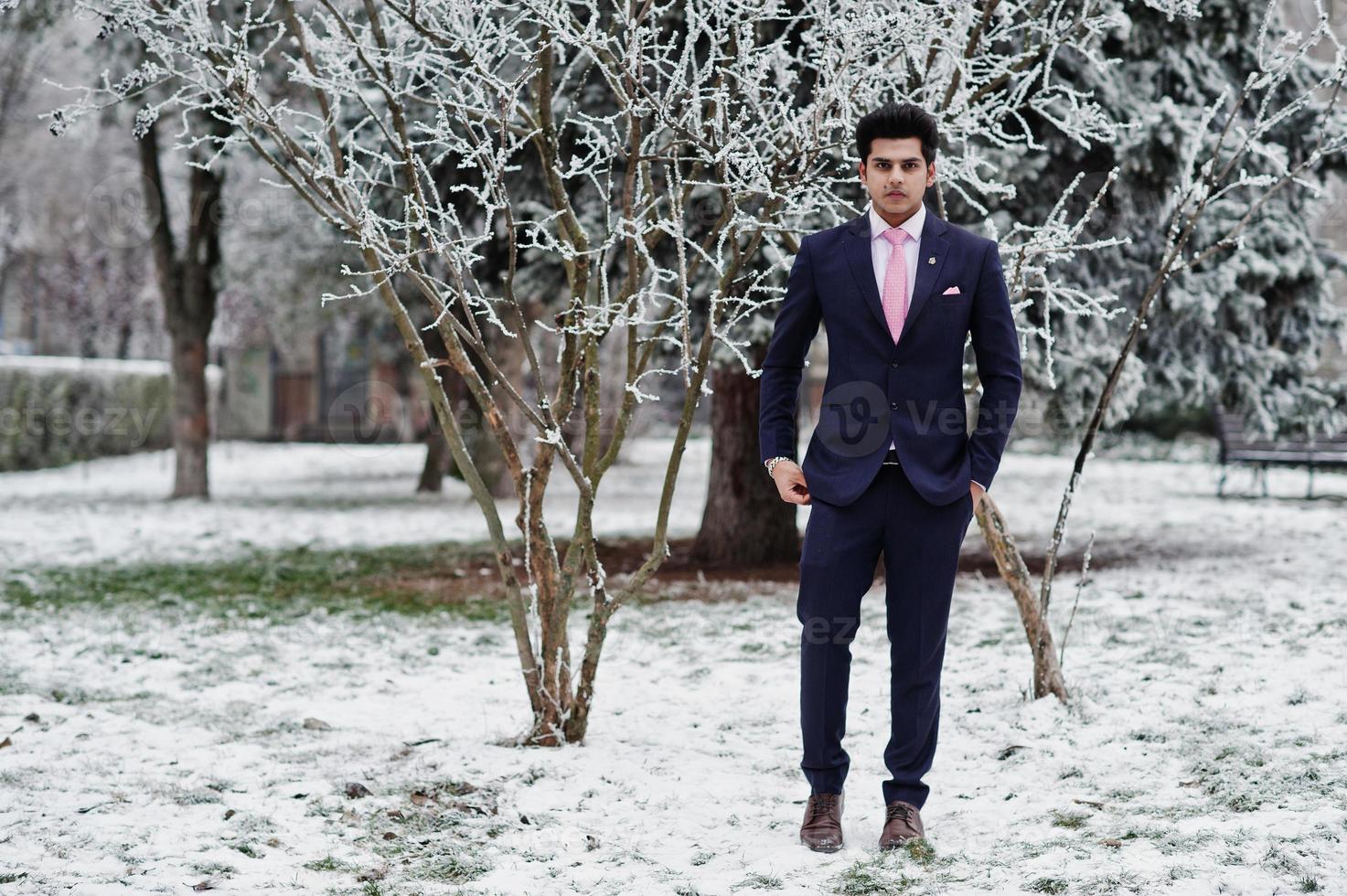 elegante modelo de hombre macho indio con traje y corbata rosa posado en el día de invierno. foto