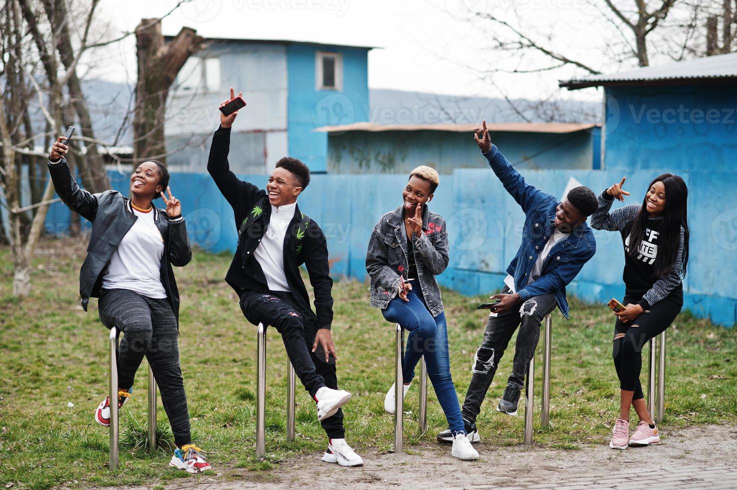 Young millennials african friends with mobile phones. Happy black people having fun together. Generation Z friendship concept. photo