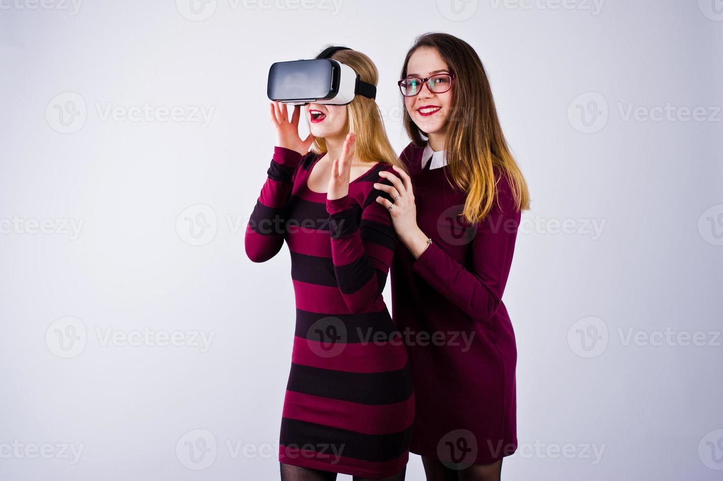 Two girls in purple dresses trying out virtual reality glasses in the studio. photo