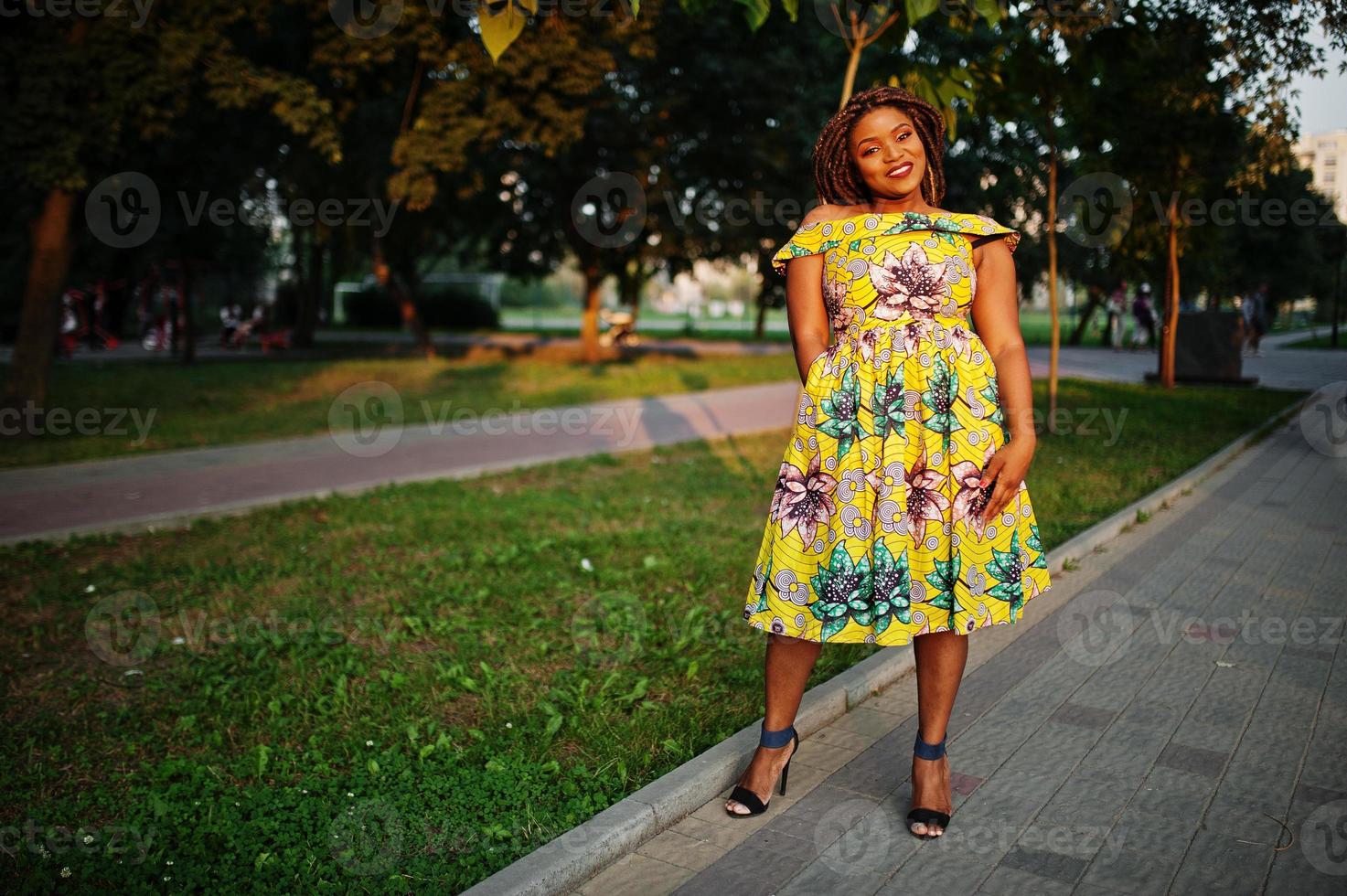 Cute small height african american girl with dreadlocks, wear at coloured yellow dress, posed at sunset. photo