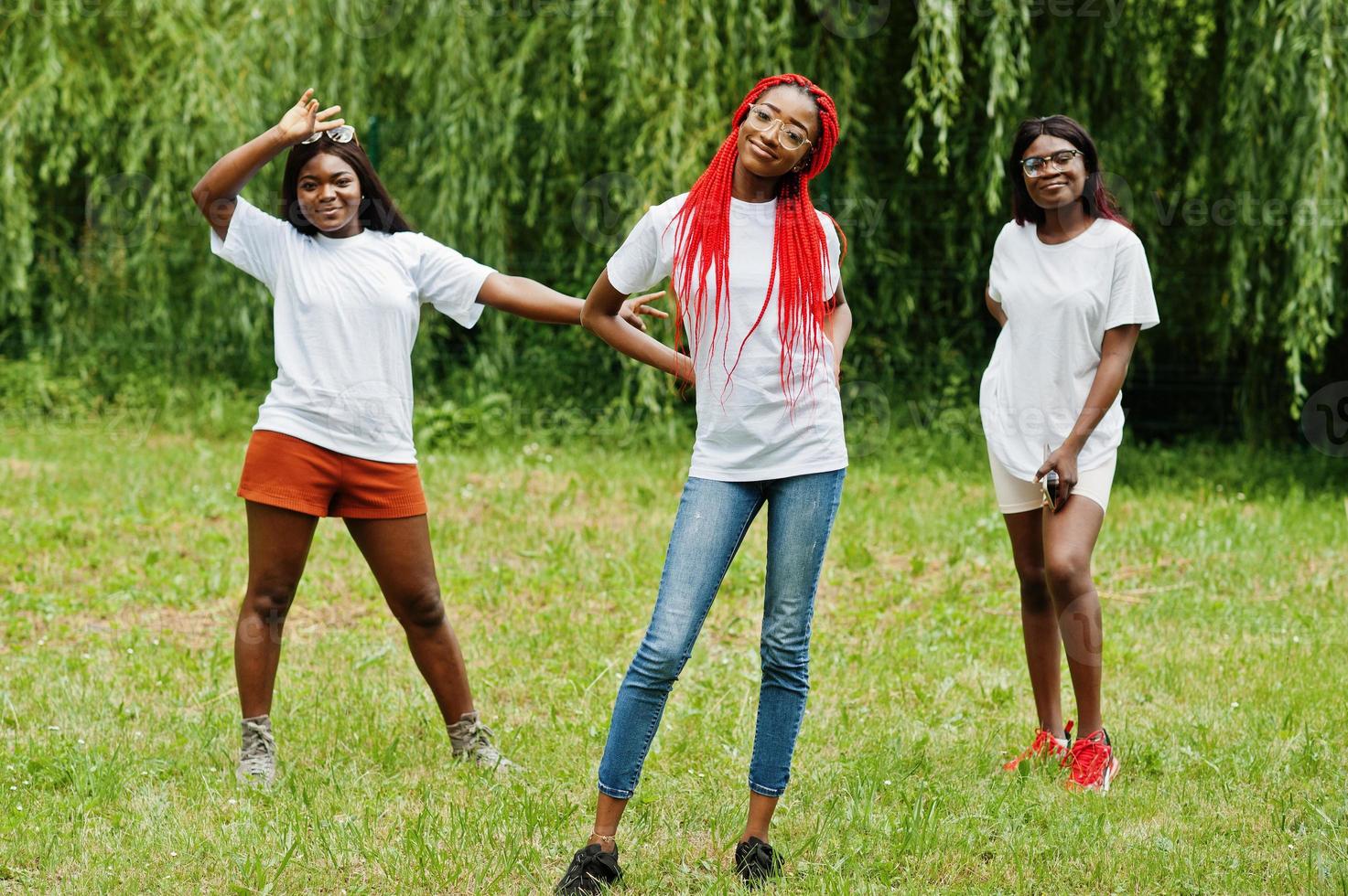 Three african american womans in park at white t-shirts. photo