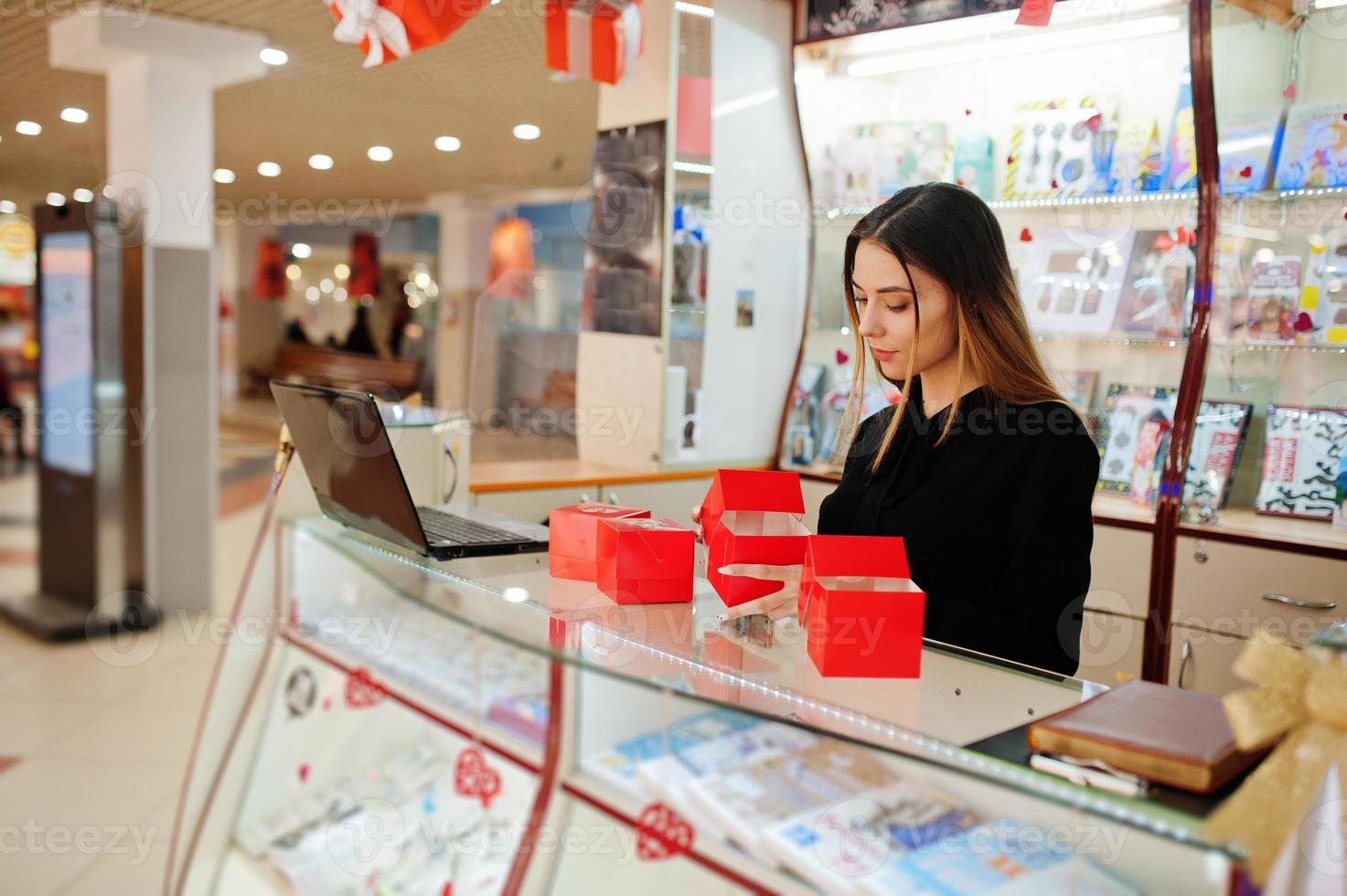 Portrait of young caucasian female woman seller hold red gift boxes. Small business of candy souvenirs shop. photo