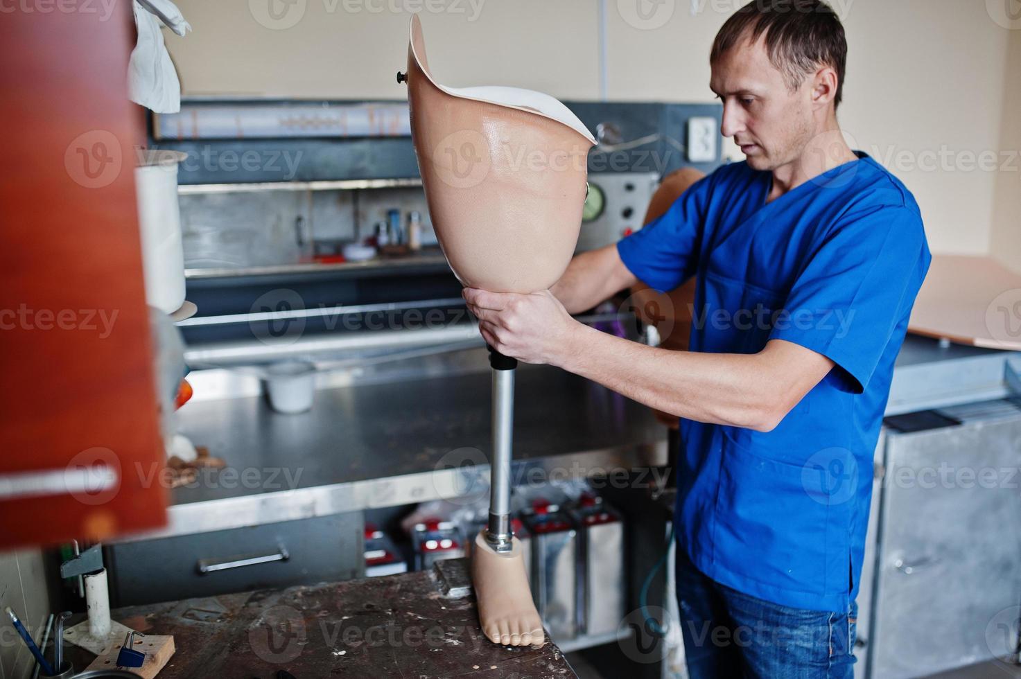 Prosthetist man making prosthetic leg while working in laboratory. photo