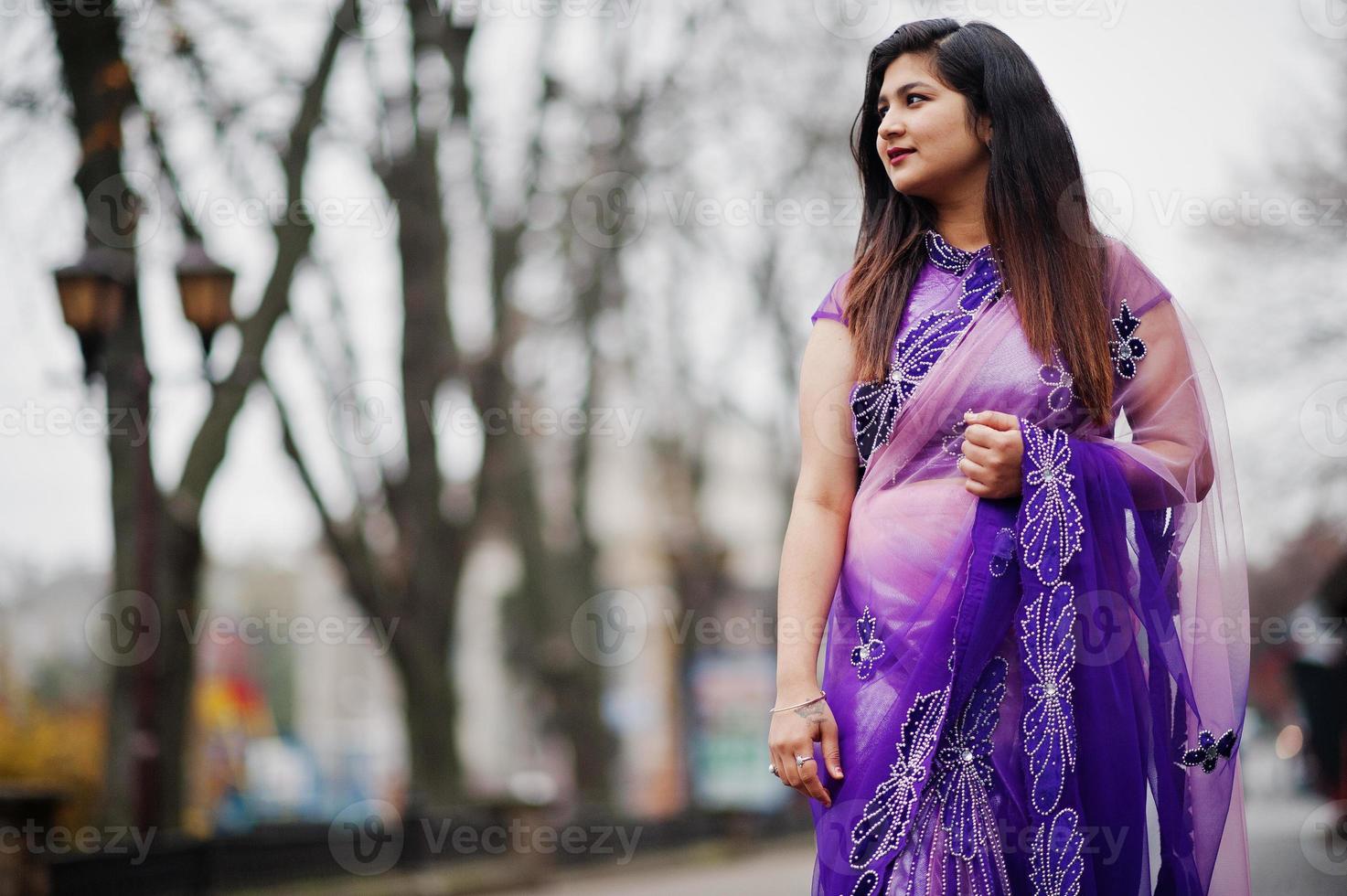 niña hindú india en el sari violeta tradicional posó en la calle. foto