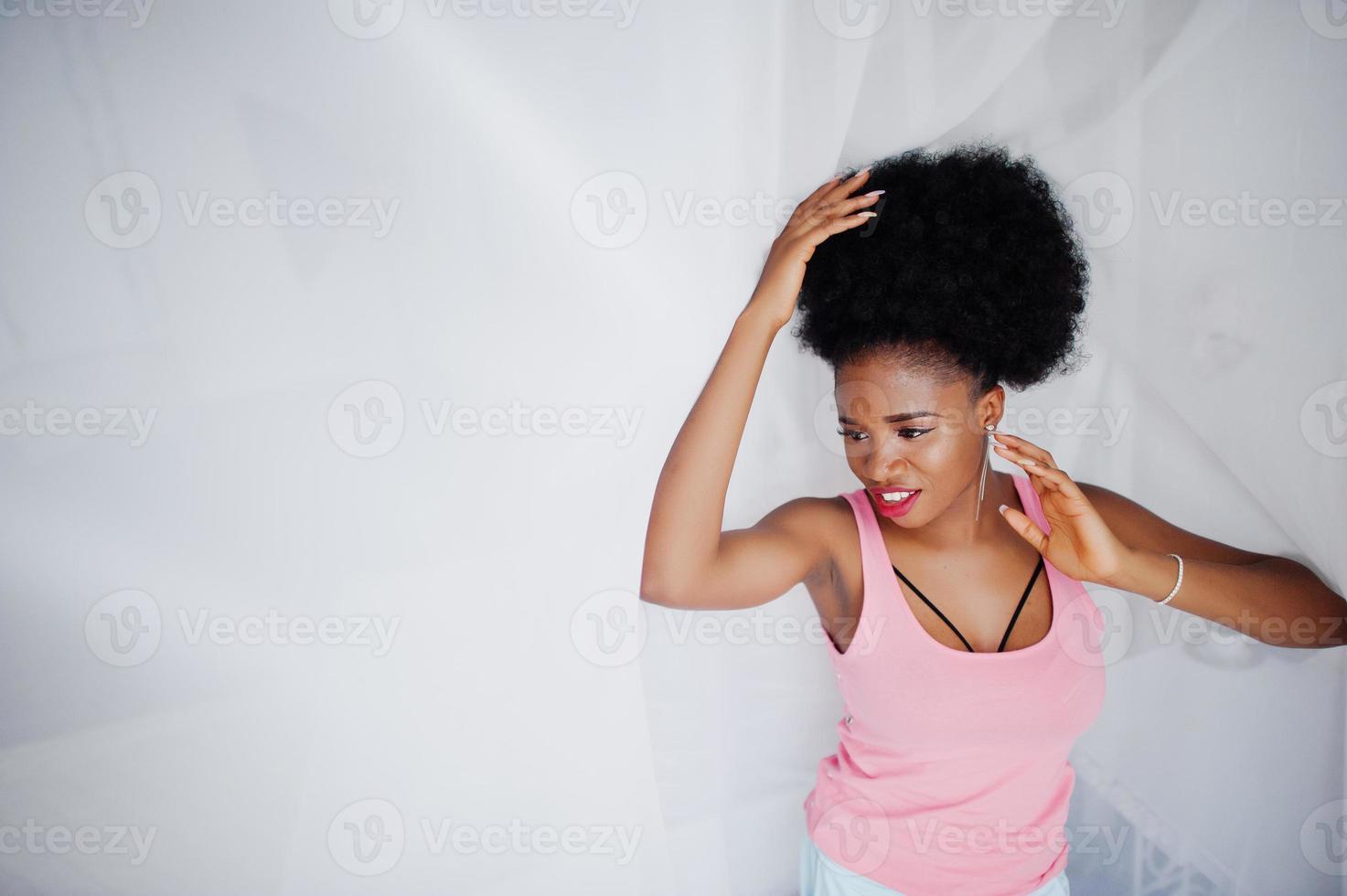 Young african american woman in pink singlet against window touching tulle. Perfect morning. photo