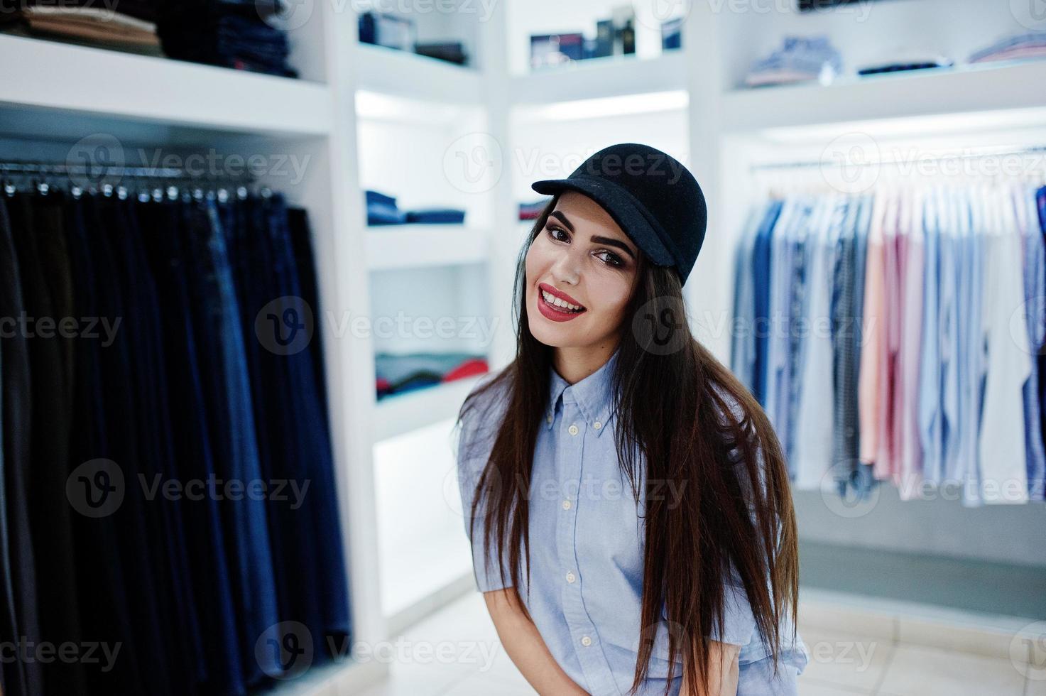 Brunette gorgeous girl in the clothing store boutique at casual clothes and cap. photo