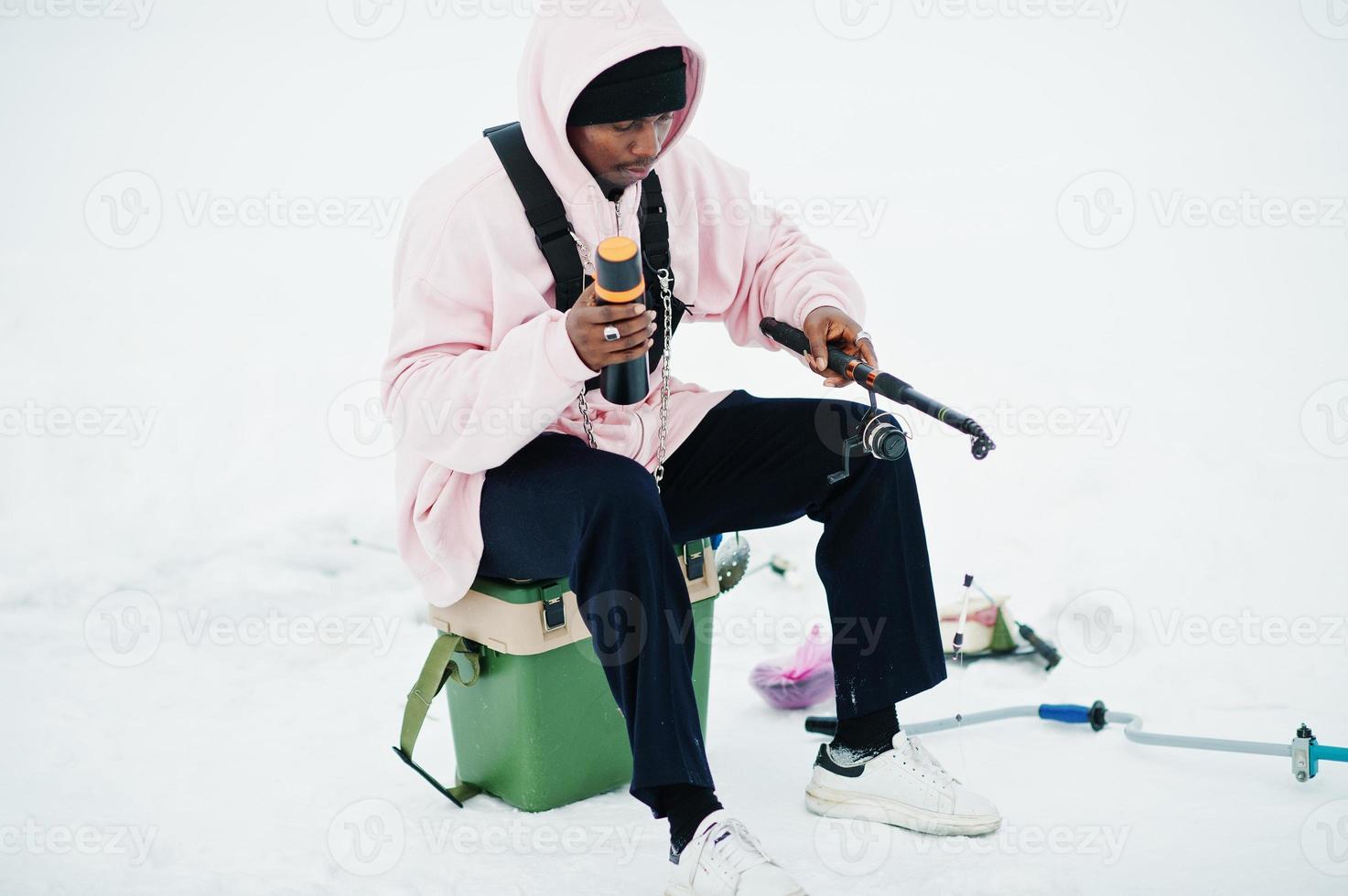 African american fisherman with fishing rod and thermos. Winter fishing. photo