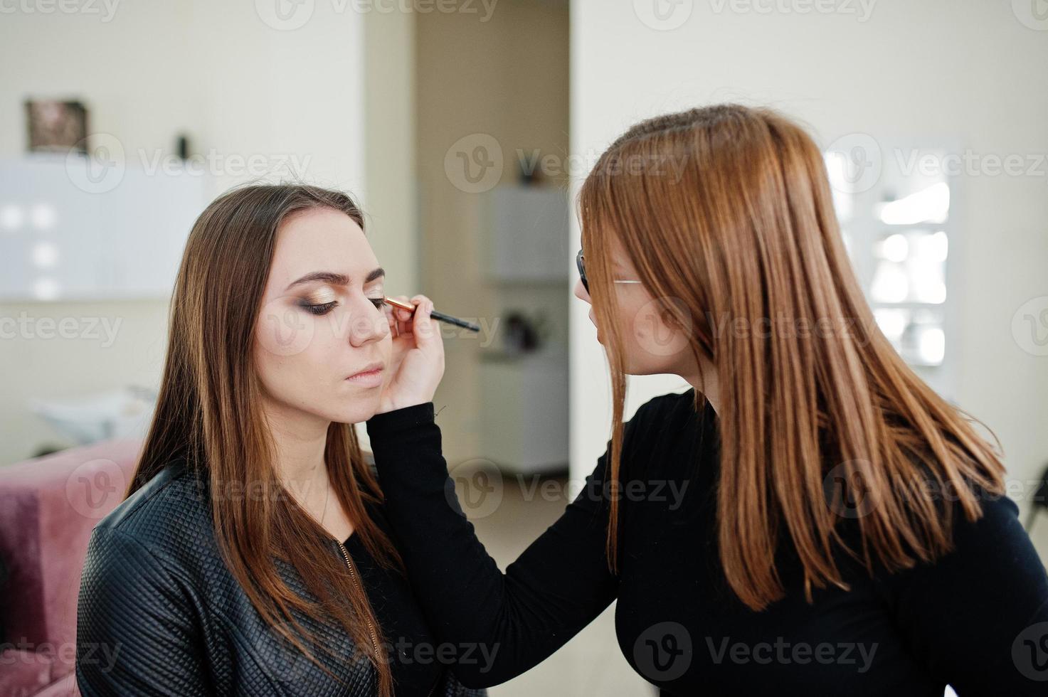 Make up artist work in her beauty visage studio salon. Woman applying by professional make up master. Beauty club concept. photo