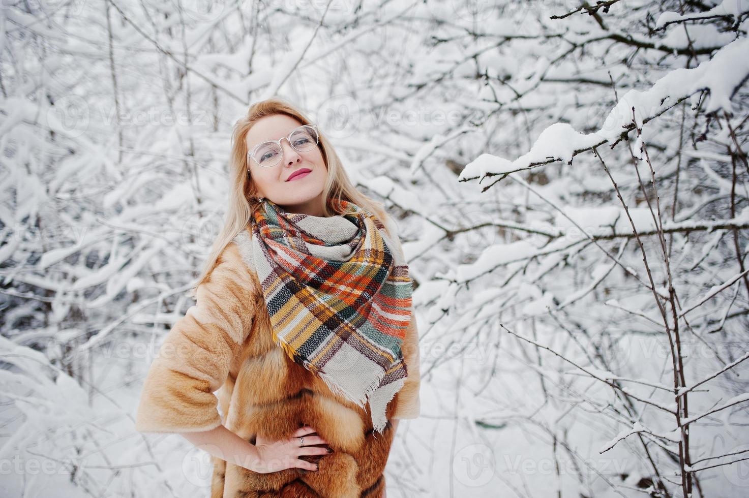 retrato de chica rubia con gafas, abrigo de piel rojo y bufanda en el día de invierno. foto