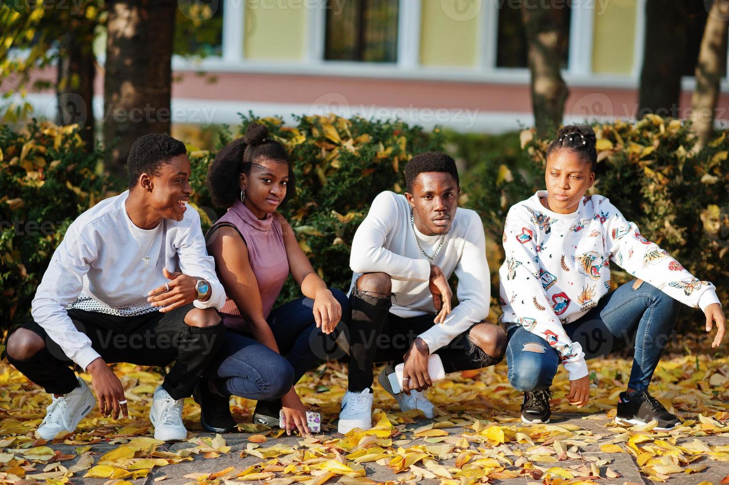 Four african friends walking the streets of an ancient city at autumn sunny day. photo