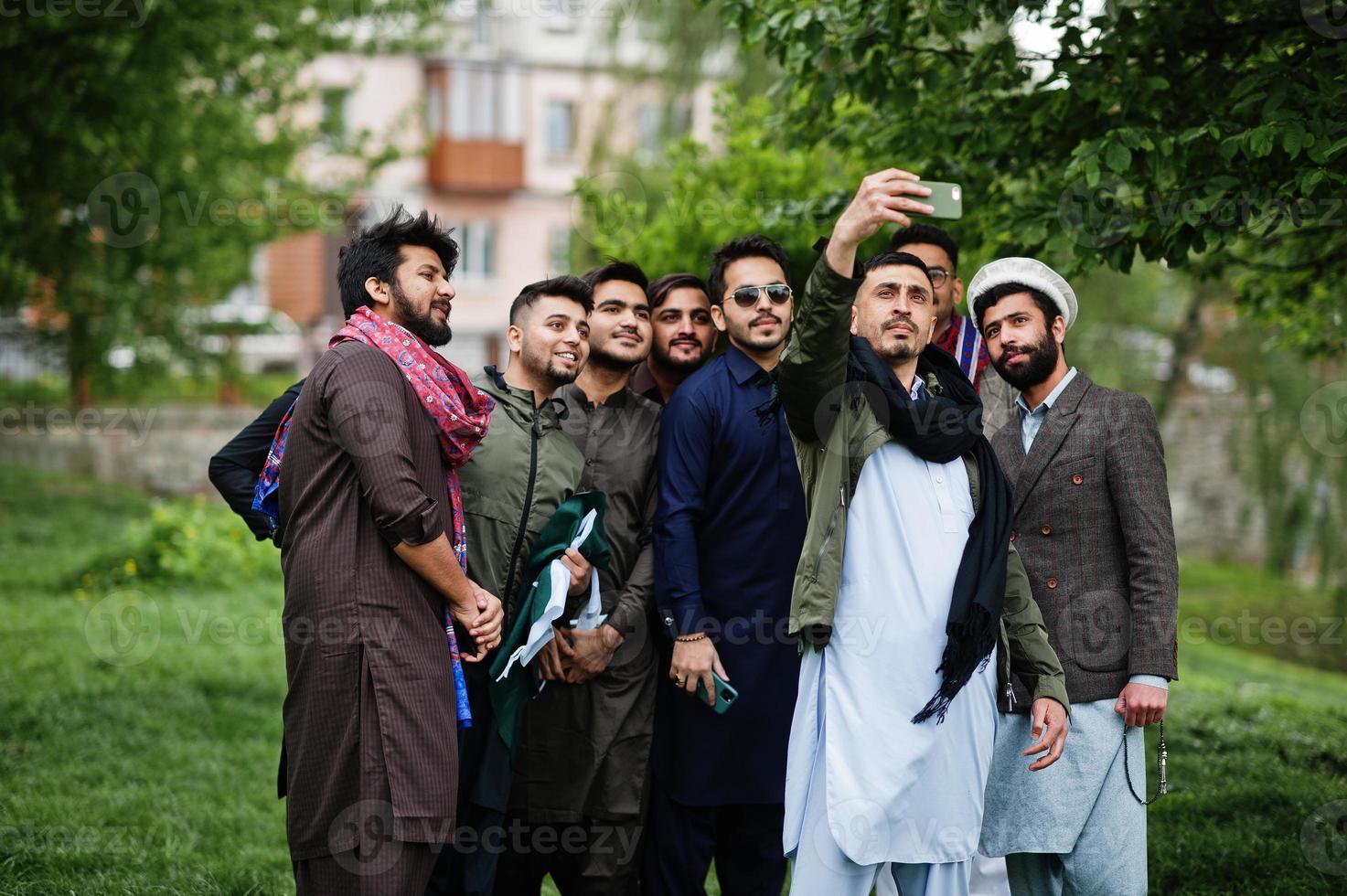 grupo de hombres paquistaníes vestidos con ropa tradicional salwar kameez o kurta haciendo selfie en el teléfono móvil. foto