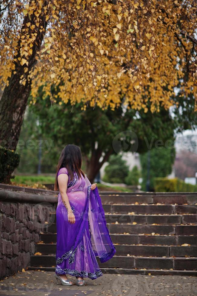 Indian hindu girl at traditional violet saree posed at autumn street. photo