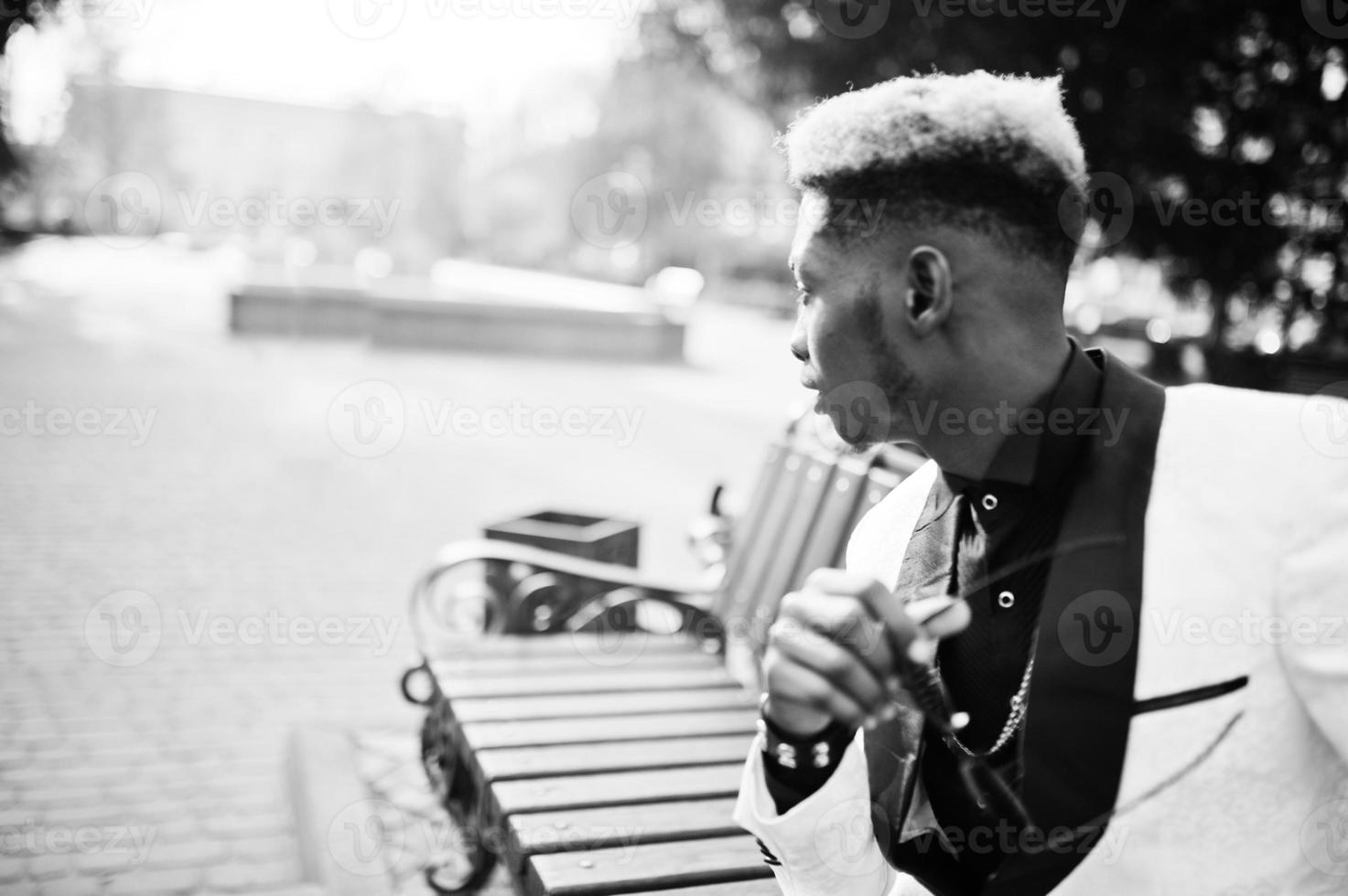 Chic handsome african american man in white suit sitting on bench. photo