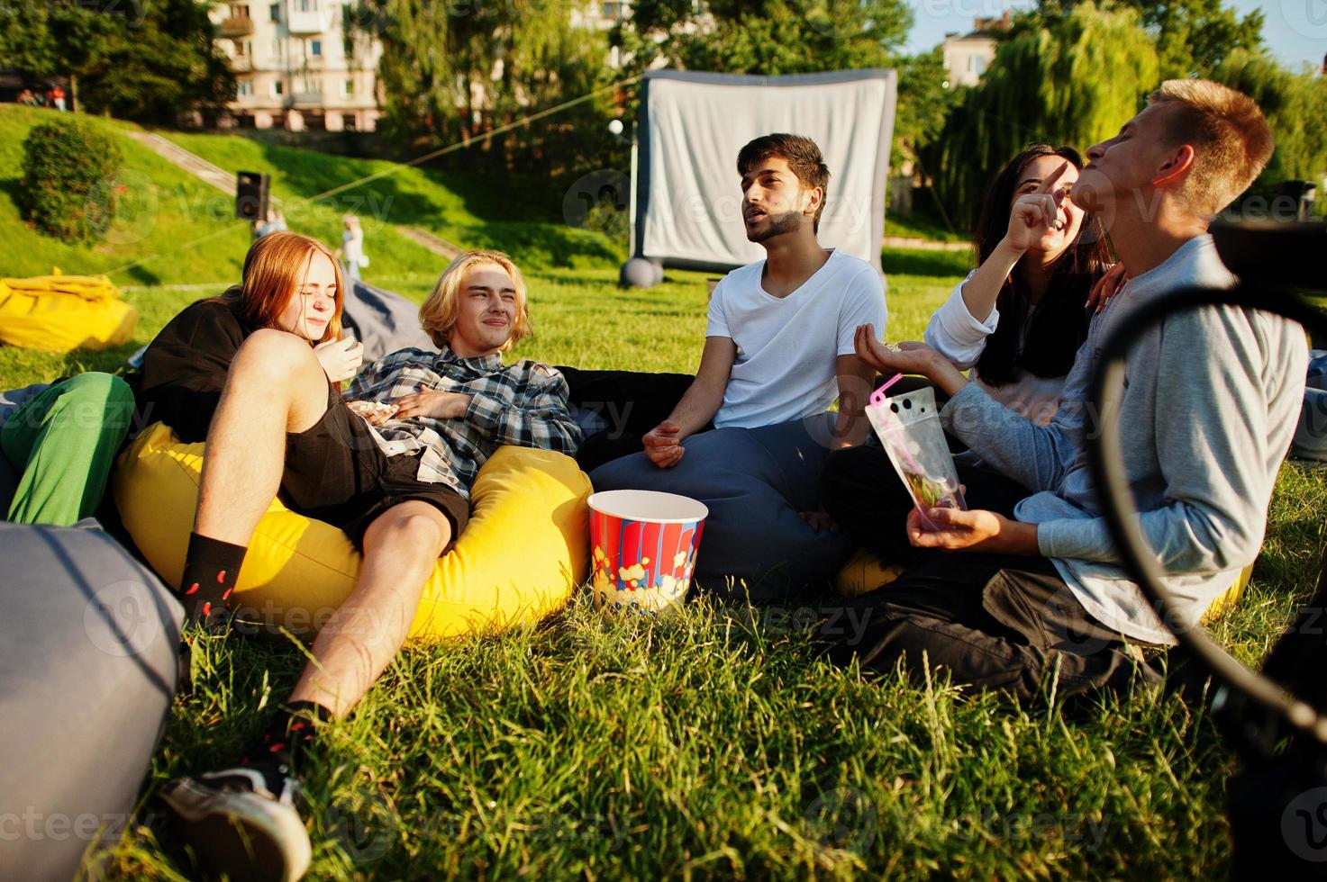 joven grupo multiétnico de personas viendo películas en poof en cine al aire libre. foto