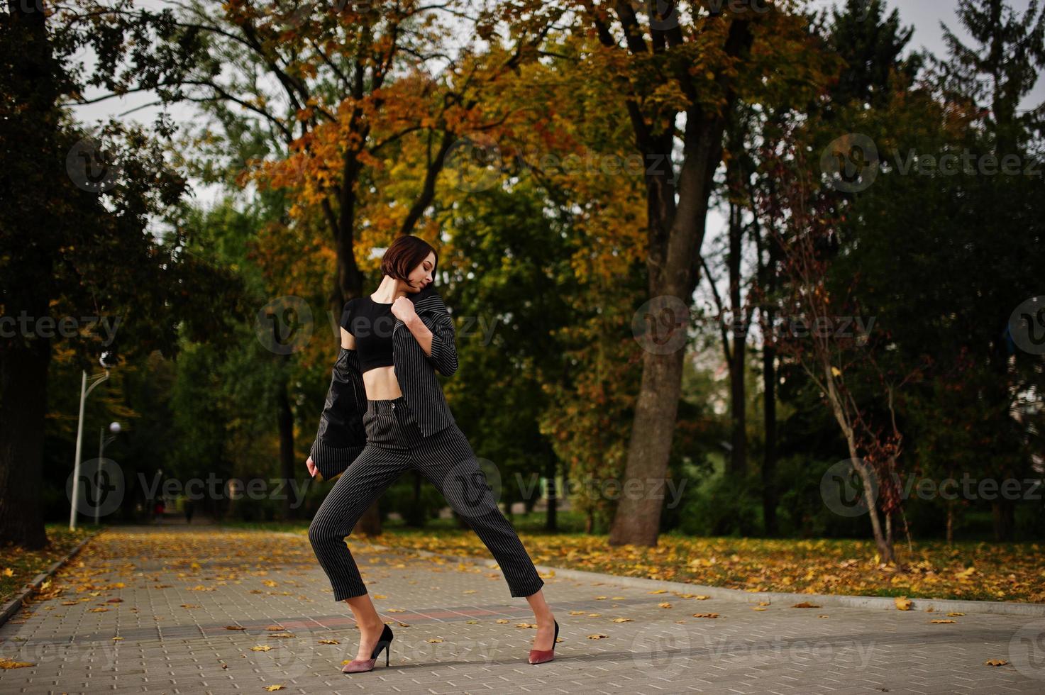 A tall leggy young beautiful and elegant model woman at formal wear posed at autumn background. photo