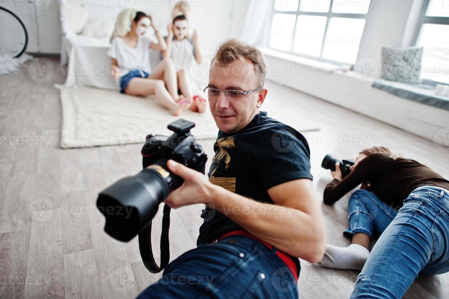 el equipo de dos fotógrafos fotografiando a las gemelas del estudio mientras hacen su propia crema para máscaras. fotógrafo profesional en el trabajo. foto