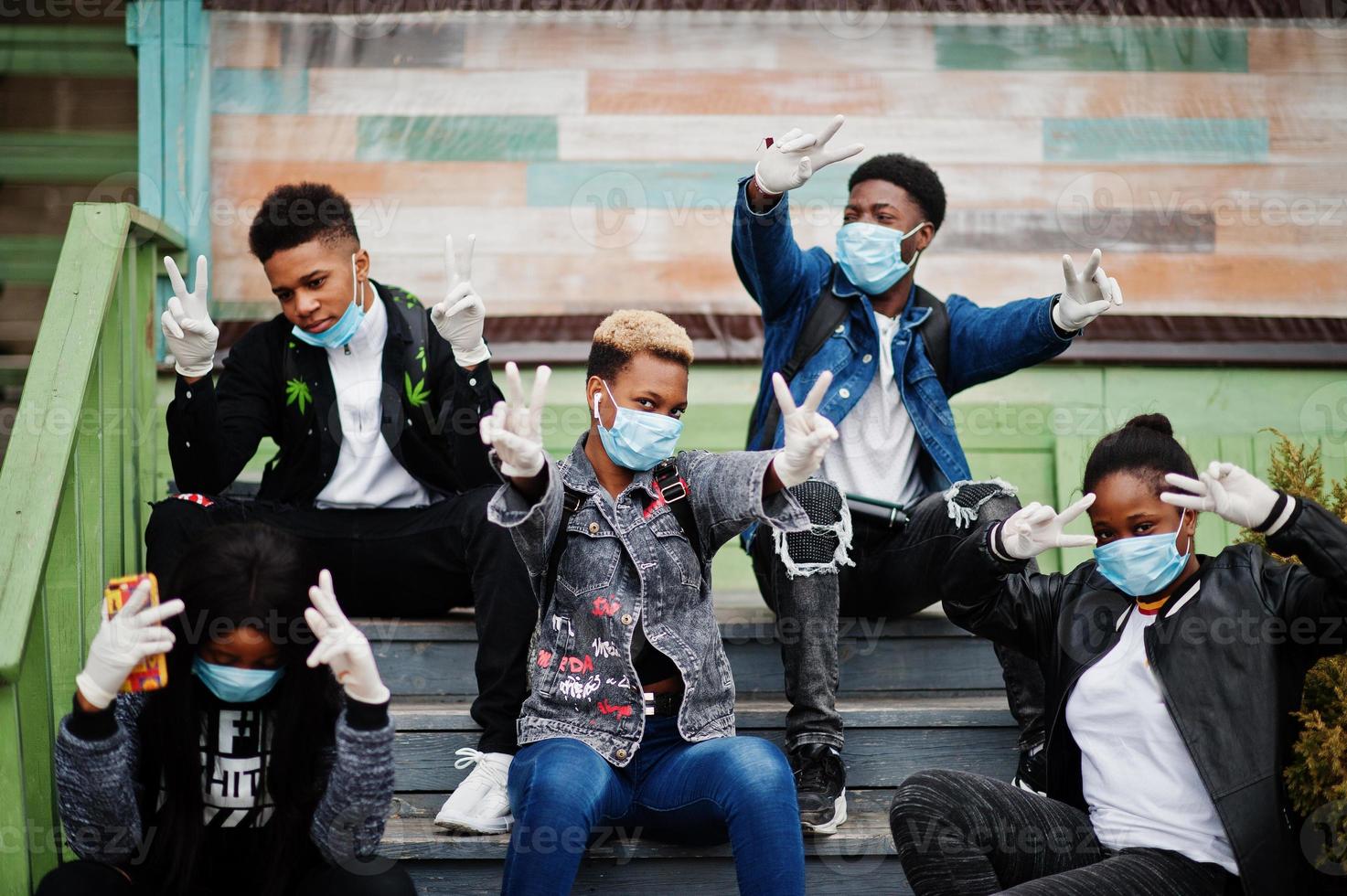 Group of african teenagers friends at park wearing medical masks protect from infections and diseases coronavirus virus quarantine. photo