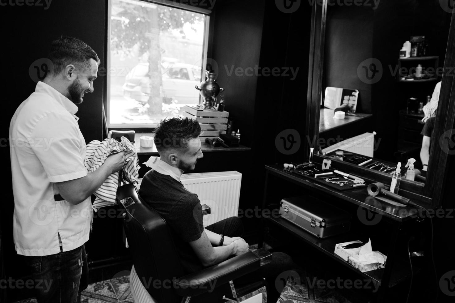 joven barbudo lavando la cabeza por el peluquero mientras se sienta en una silla en la barbería. alma de barbero. foto