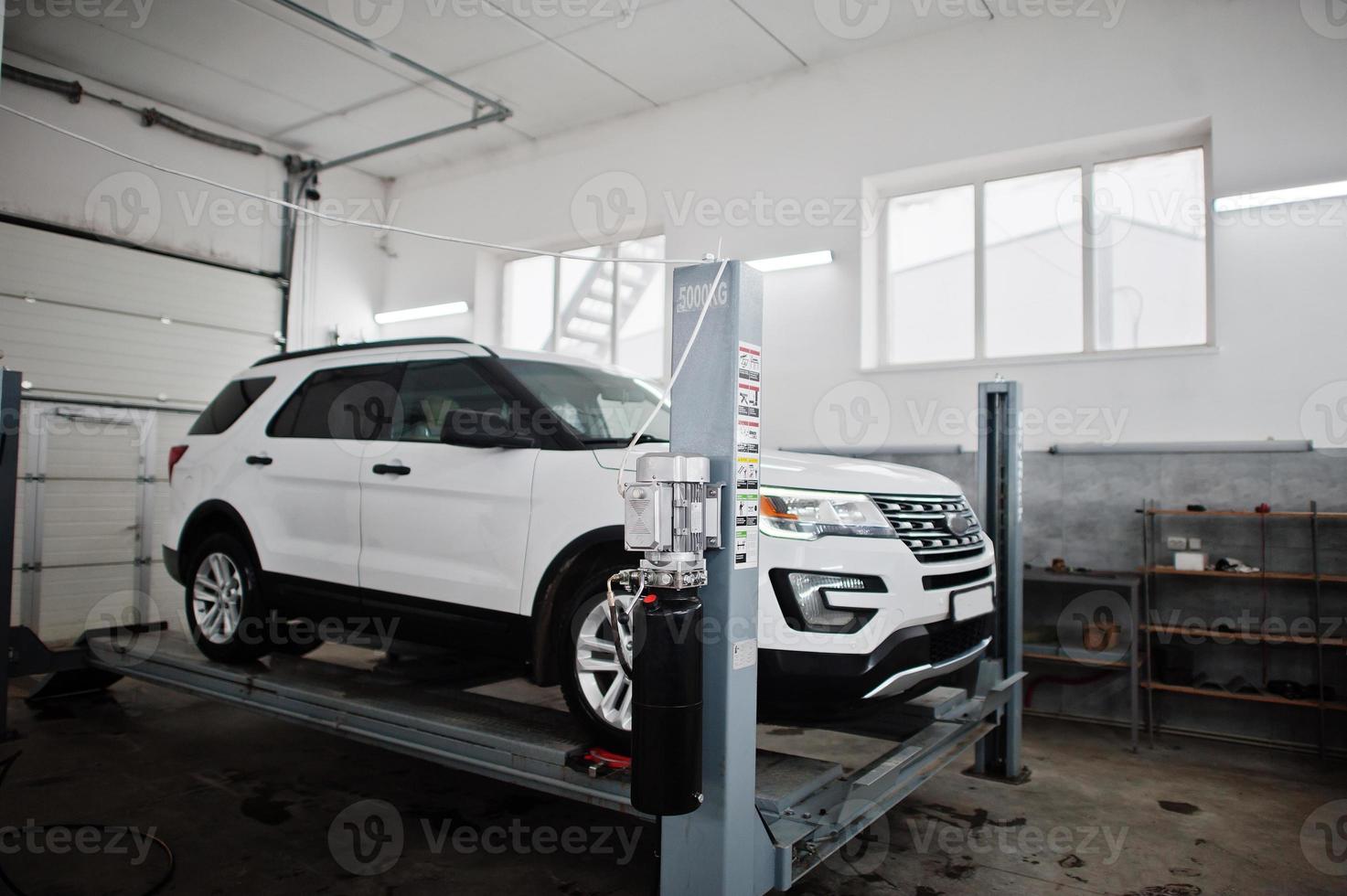 American SUV car on stand for wheels alignment camber check in workshop of service station. photo