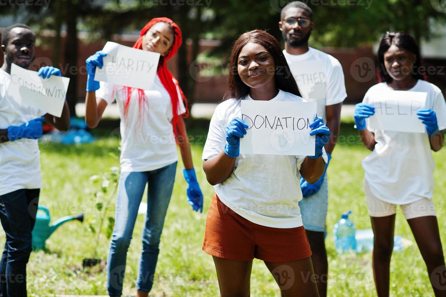 Group of happy african volunteers hold blank board with donation sign in park. Africa volunteering, charity, people and ecology concept. photo