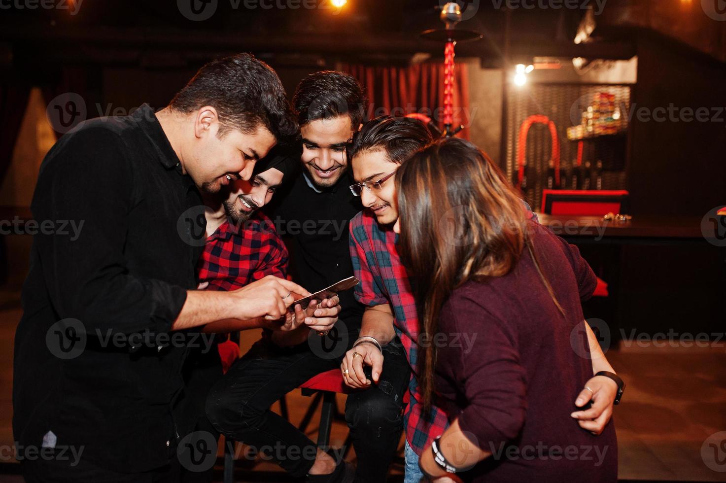 Group of indian friends sitting at lounge bar, having rest and look at menu. photo