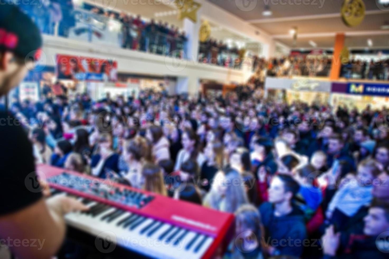 Blured photo crowded concert hall with scene stage lights with people at rock performance.