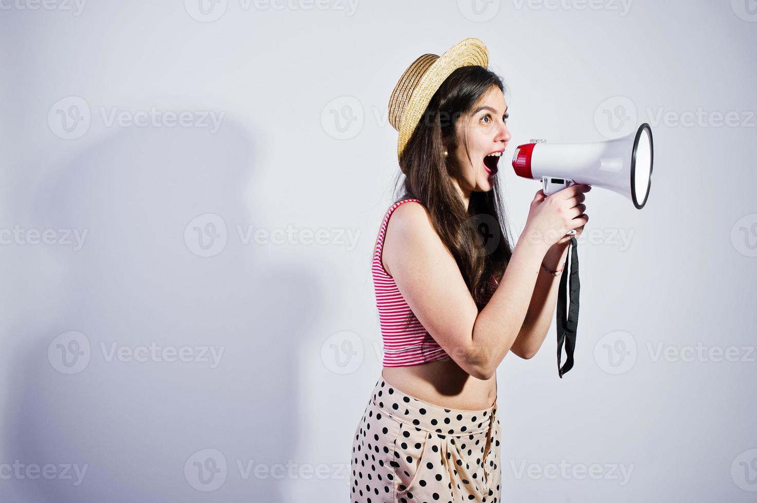 Portrait of a gorgeous young girl in swimming suit and hat talks into megaphone in studio. photo