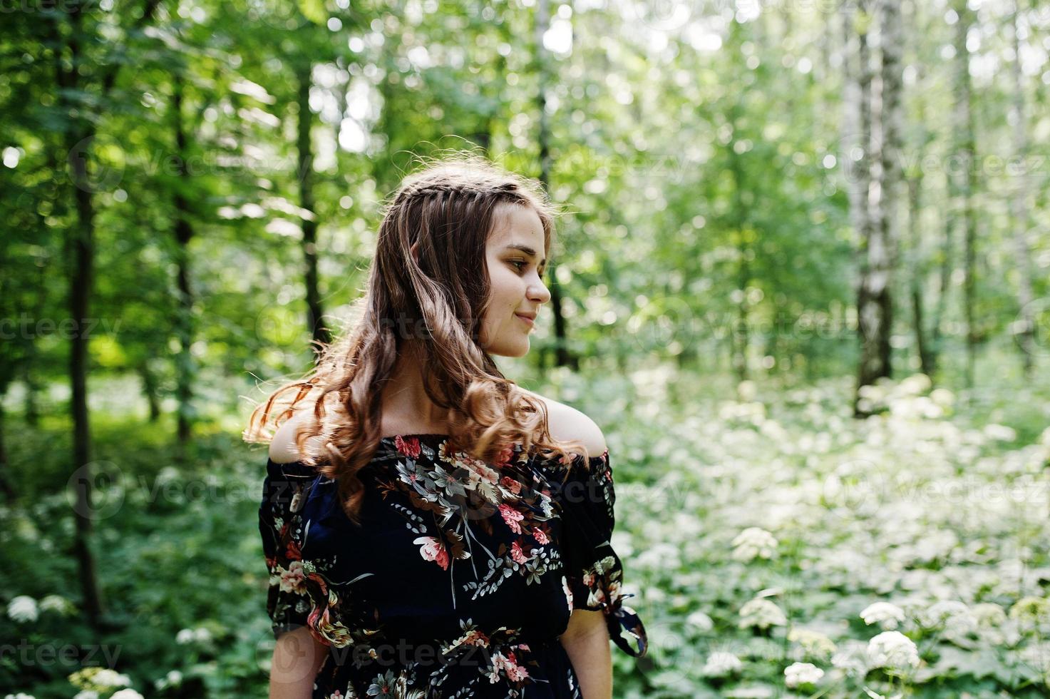 retrato de una joven fabulosa con un bonito vestido con un elegante peinado rizado posando en el bosque o en el parque. foto