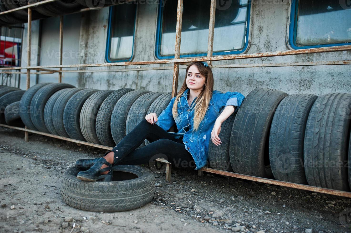 Young hipster girl in jeans jacket and head scarf at tire fitting zone. photo