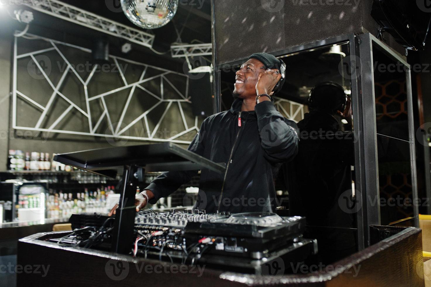 African american dj play music on decks at night club. photo