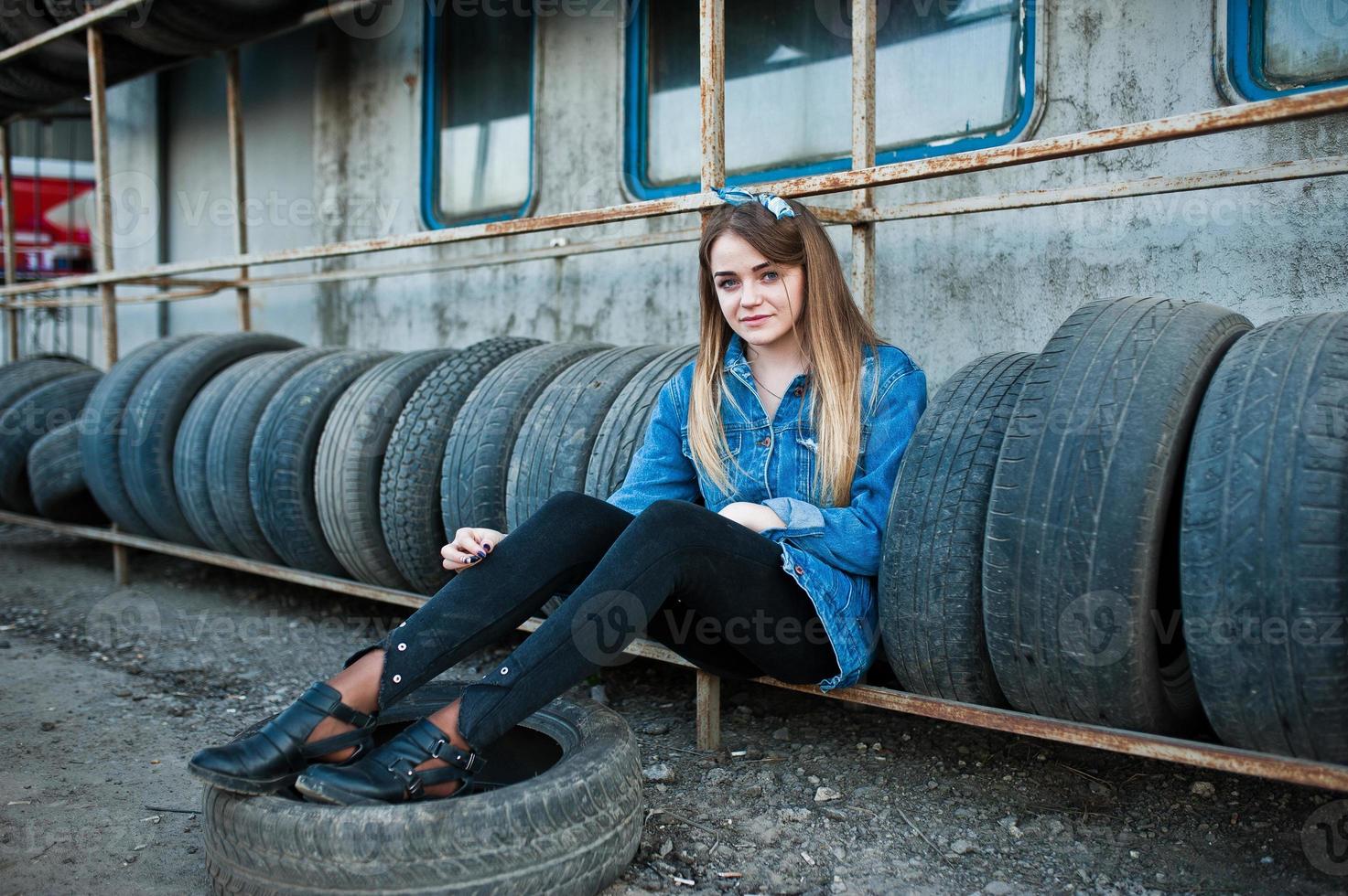 Young hipster girl in jeans jacket and head scarf at tire fitting zone. photo