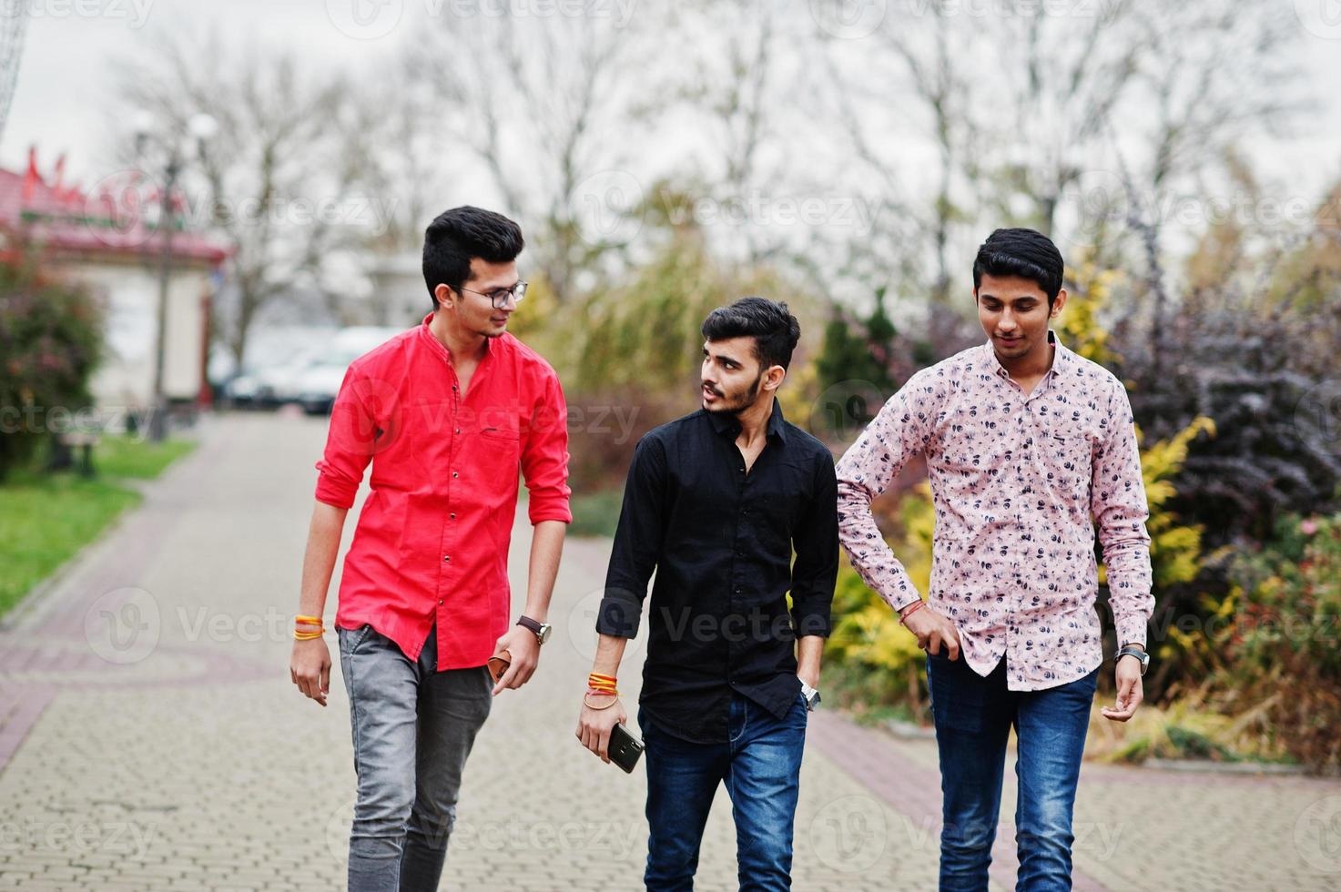 Three indian guys students friends walking on street. photo