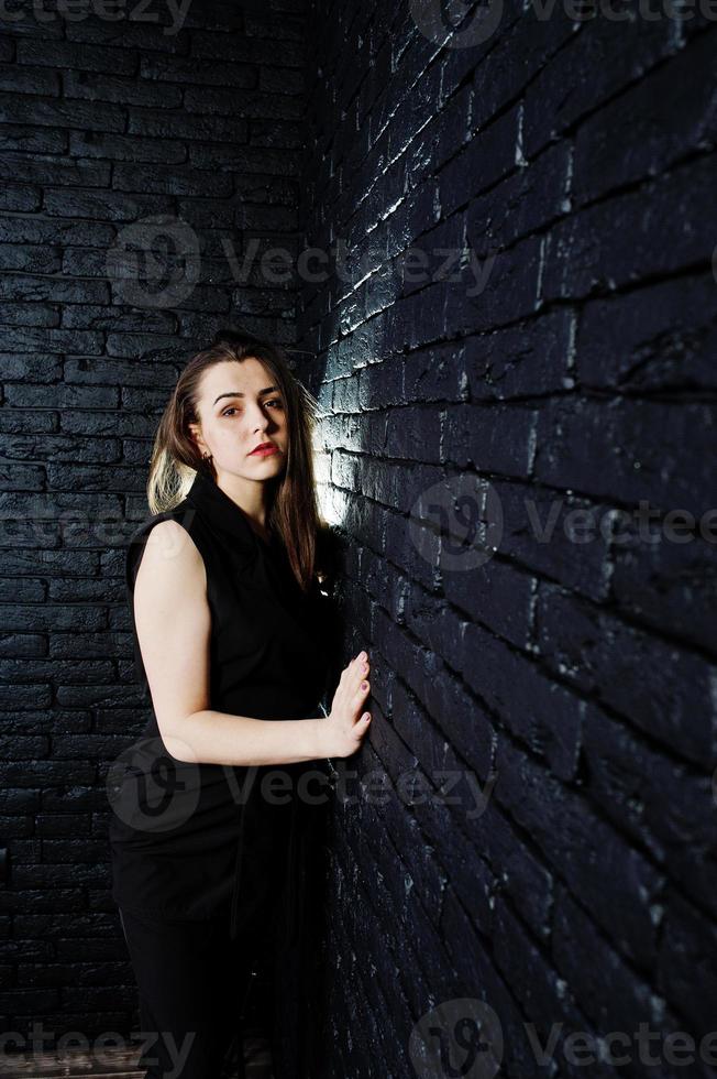 retrato de una hermosa morena con mono negro en el estudio junto a la pared de ladrillos. foto