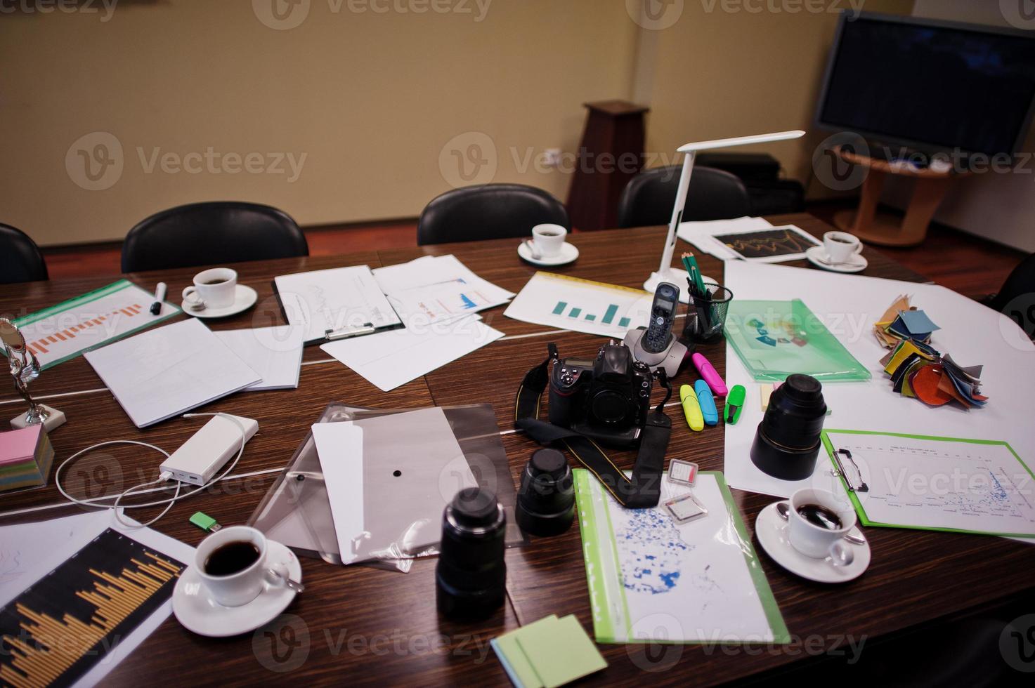 Modern business office interior containing tables and chairs, laptop, camera and office supplies with no employees. photo