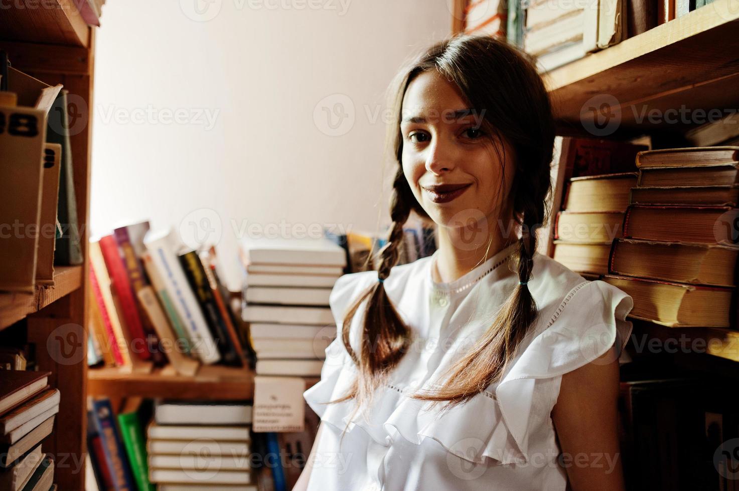 chica con coletas en blusa blanca en la antigua biblioteca. foto