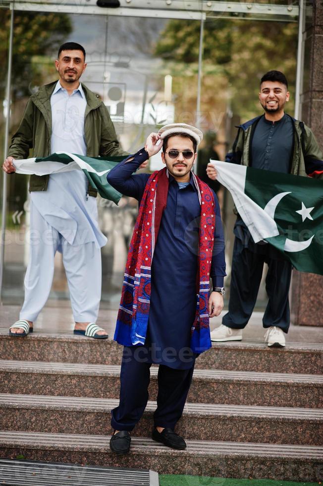 grupo de hombres paquistaníes vestidos con ropa tradicional salwar kameez o kurta con banderas de pakistán. foto