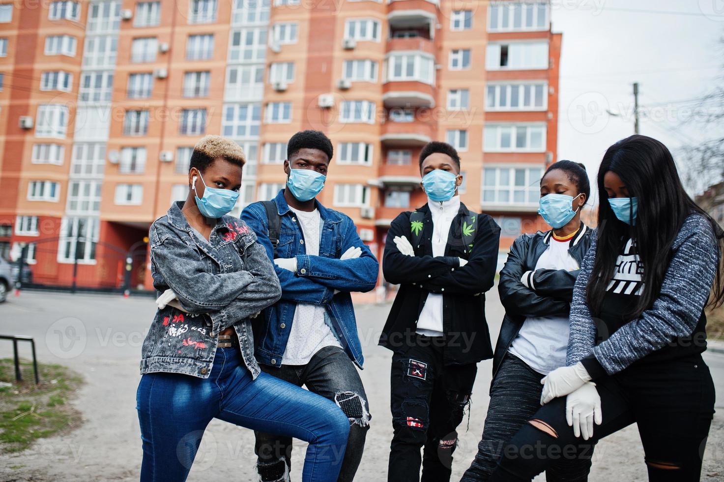 Group of african teenagers friends against empty street with building wearing medical masks protect from infections and diseases coronavirus virus quarantine. photo