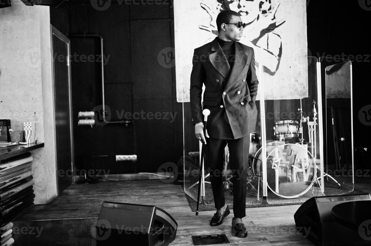 Stylish african american gentleman in elegant black jacket and sunglasses, holding retro walking stick as cane flask or tippling cane with golden diamond ball handle. Rich fashionable afro man. photo