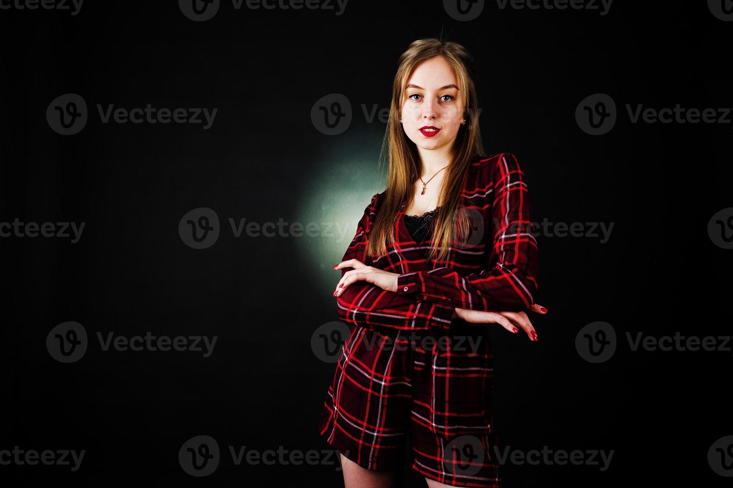 Young blonde girl in checkered dress at black background. photo