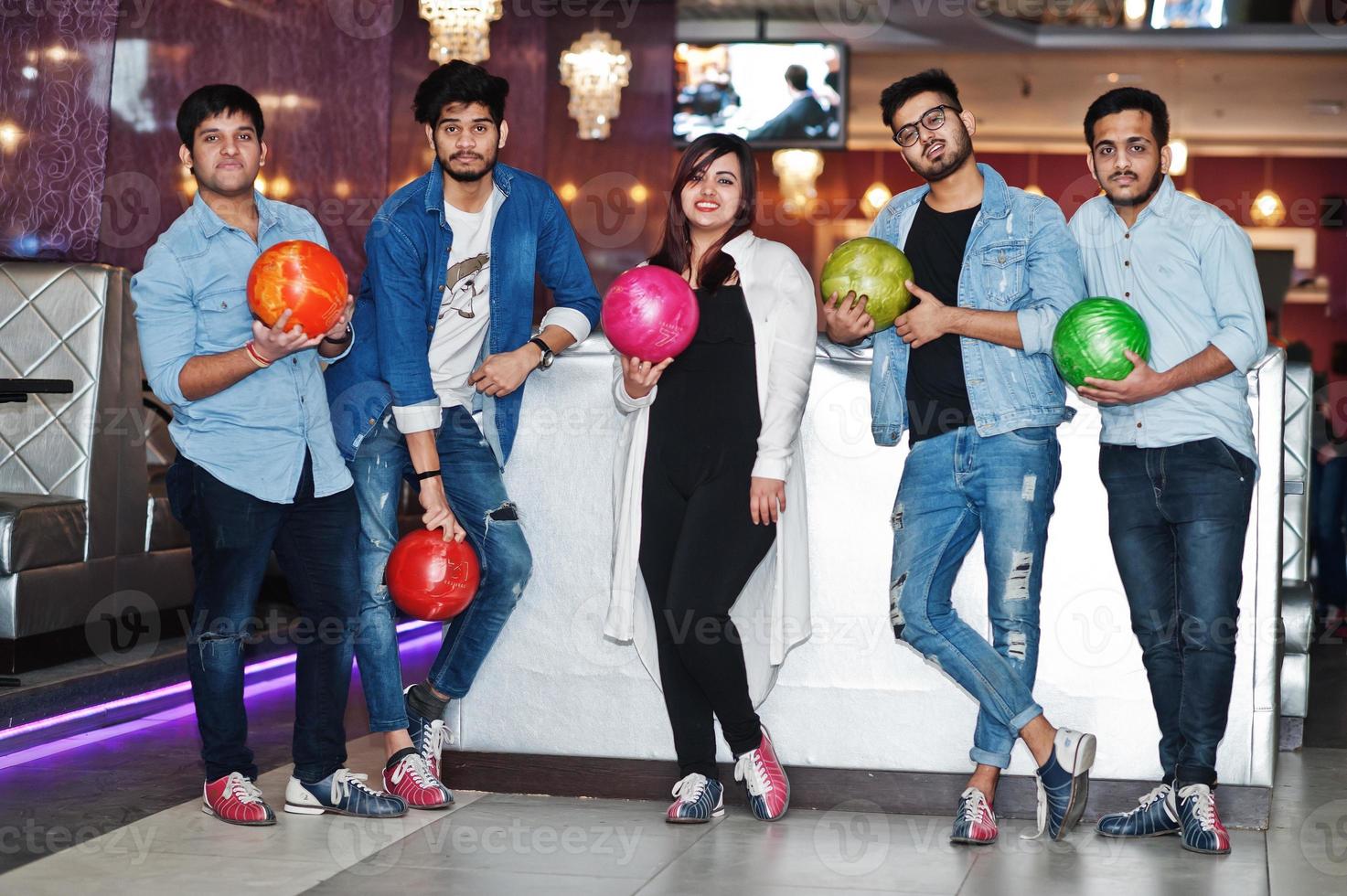 grupo de cinco pueblos del sur de asia descansando y divirtiéndose en el club de bolos con pelotas en las manos. foto