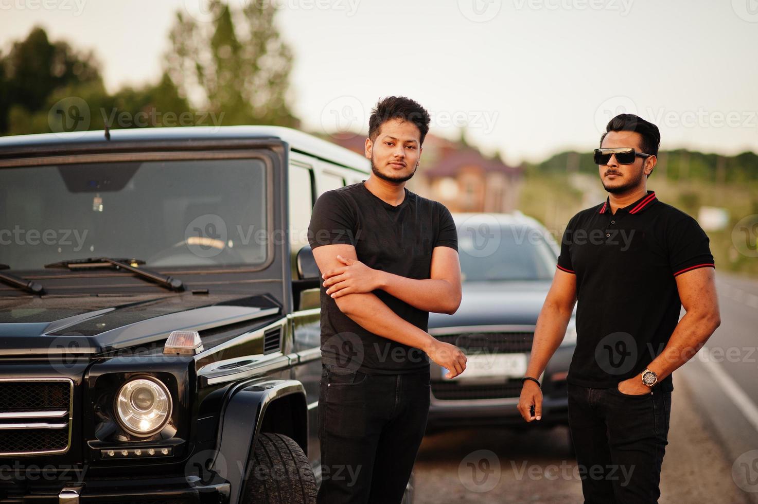 dos hermanos asiáticos se visten de negro y posan cerca de los autos todoterreno. foto