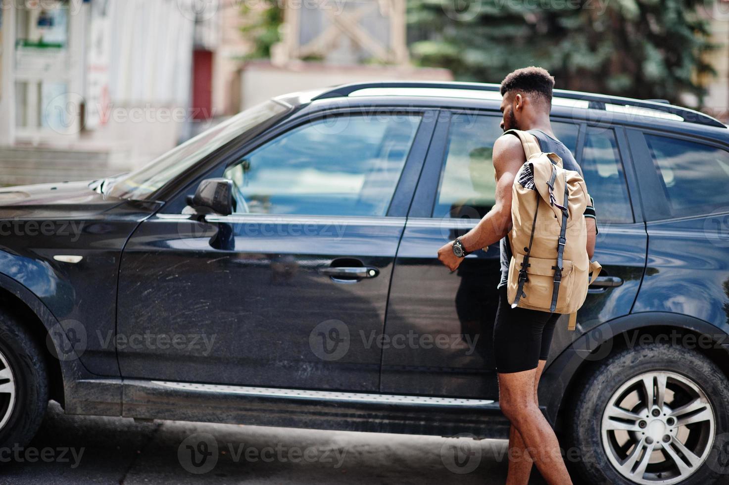 African american male athlete sport man with backpack against his black suv car before training. photo