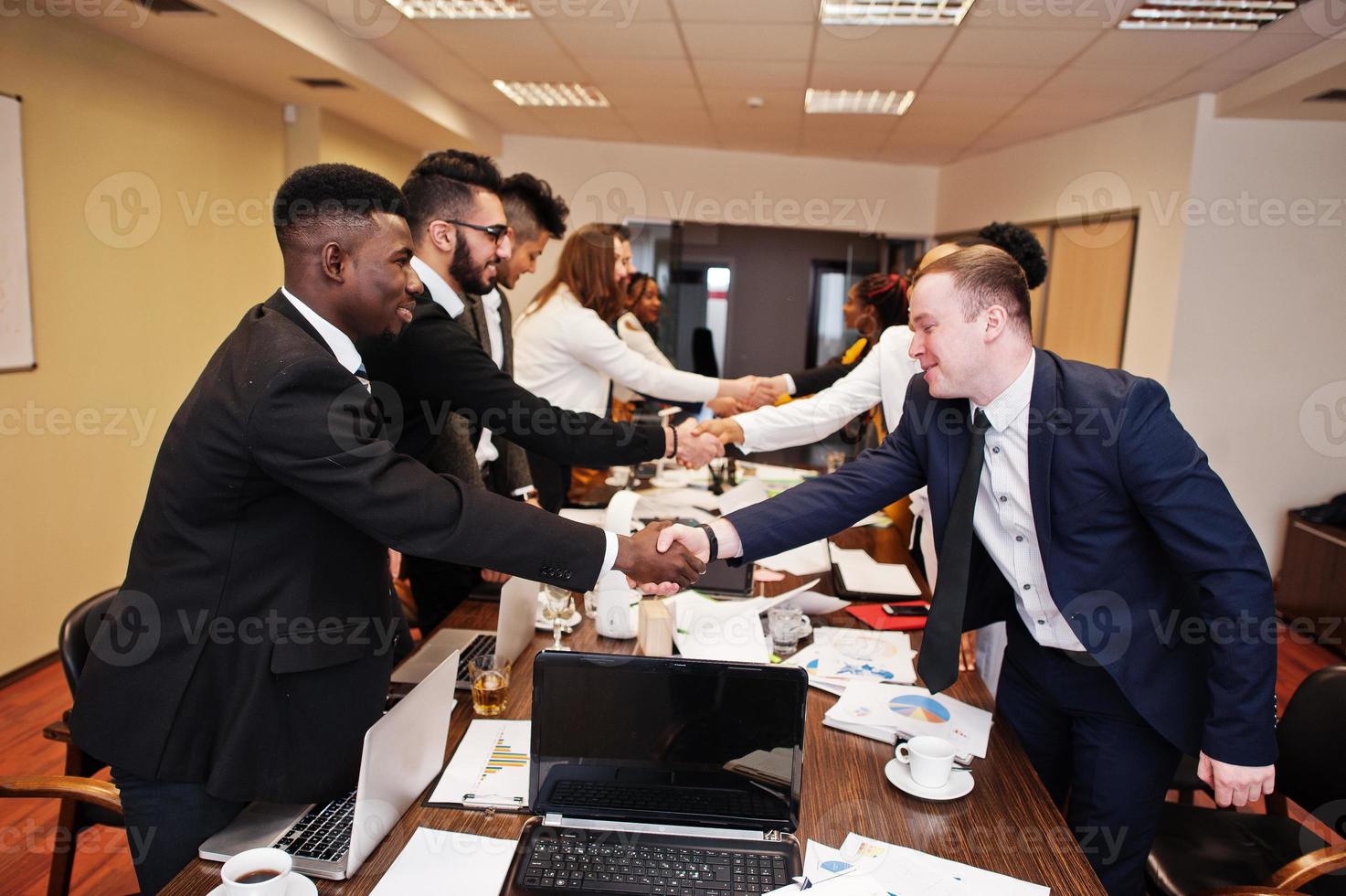 Good deal. Multiracial business team addressing meeting around boardroom table and shaking hands each other. photo