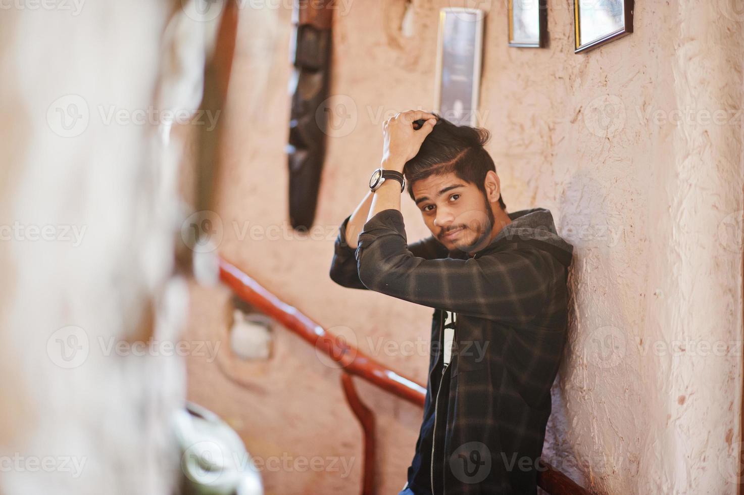 Beard asian man in casual wear stand inside house on stairs against window. photo