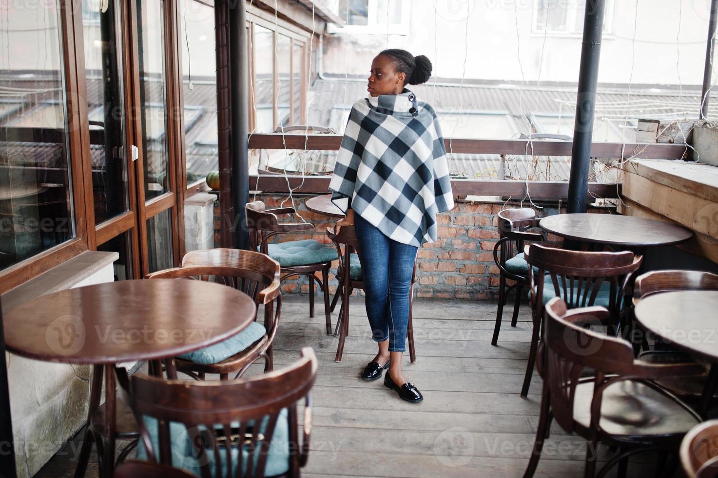 African woman in checkered cape posed outdoor cafe terrace. photo